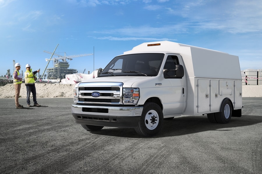 Deux travailleurs de la construction près d’un fourgon tronqué Ford série E 2026 avec carrosserie modifiée d’entrepreneur