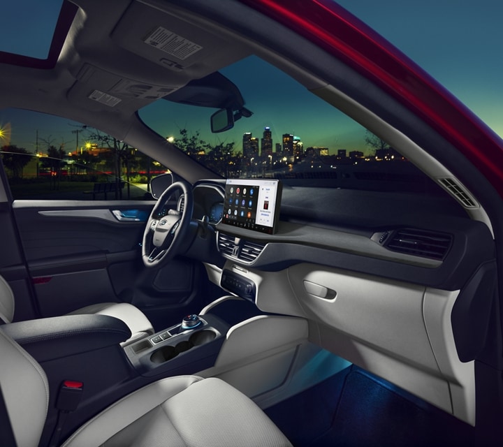 Ford Escape® 2023 couleur rouge rapide la nuit, avec la porte du côté passager ouverte avec paysage urbain en arrière-plan