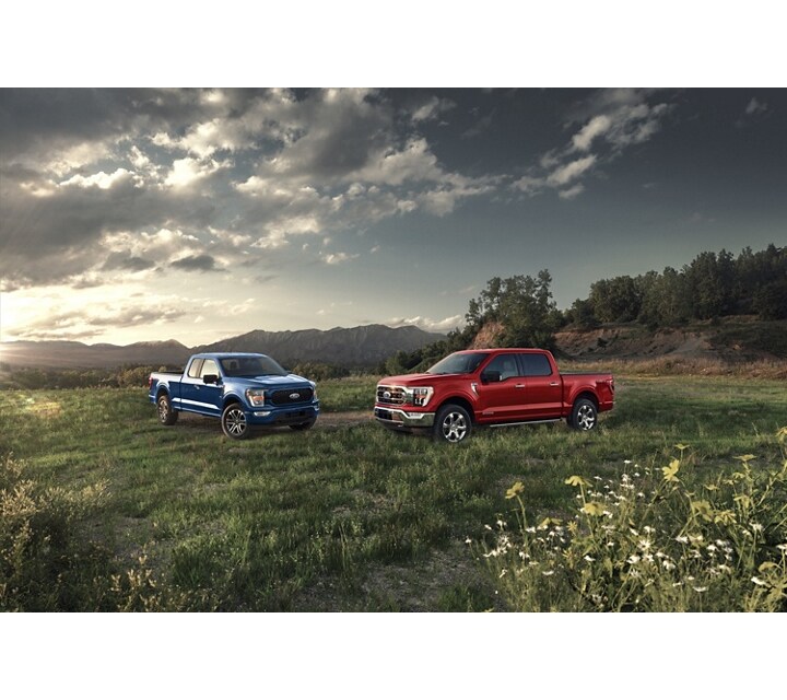 Image d’un Ford F-150® XL 2023 couleur bleu Atlas et d’un F-150® XLT en rouge course stationnés sur un point de vue montagneux