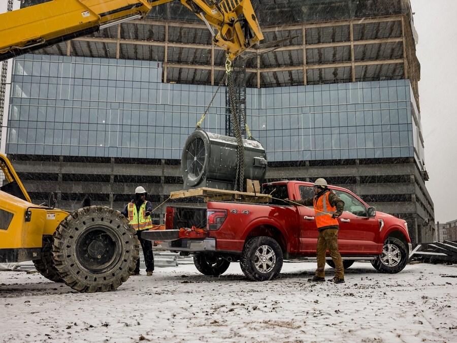 Une personne se tient derrière un camion Ford F-150® 2024 alors qu'un moteur à turbine géant est descendu dans la caisse du camion