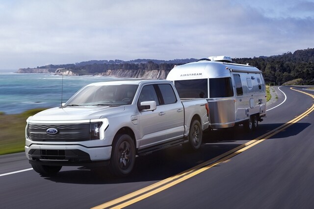 Ford F-150® Lightning® 2023 couleur argent emblématique tirant une caravane Airstream près d’un lac