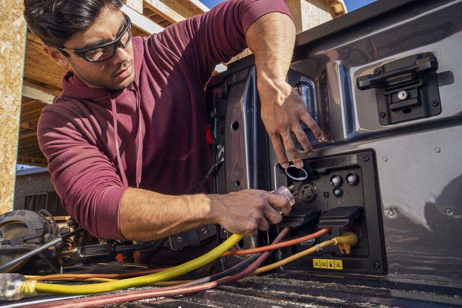 Homme branchant des cordons dans des prises de caisse Pro Power à bord sur le Ford F-150® Lightning® 2023