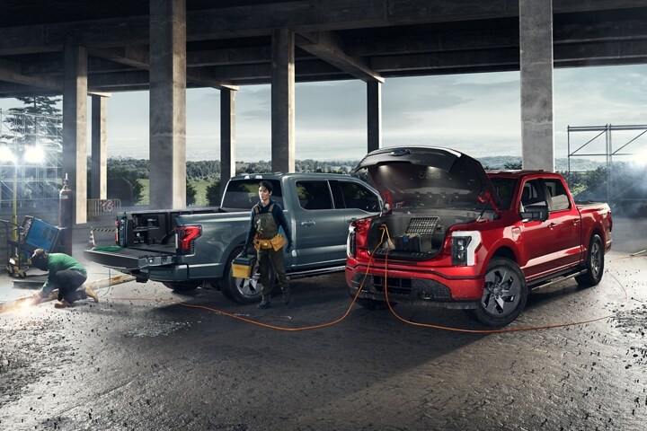 Deux camions F-150® Lightning® 2023 sur un chantier de construction avec la génératrice Pro Power embarquée utilisée pour alimenter un soudeur TIG