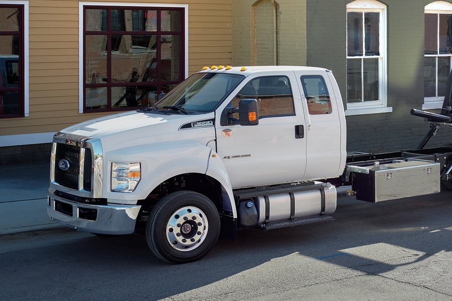 Une personne entrant dans le Ford F-650 2025 à cabine double avec plateau à recul et camion de remorquage en blanc Oxford
