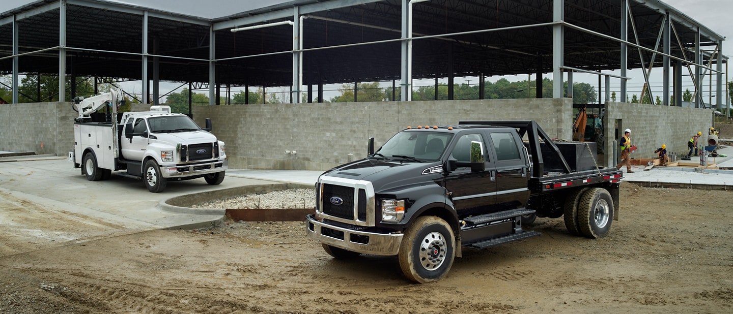 Ford F-750 2025 à cabine double avec aménagement en blanc Oxford et Ford F-750 2025 à cabine six places avec aménagement en noir agate sur un chantier