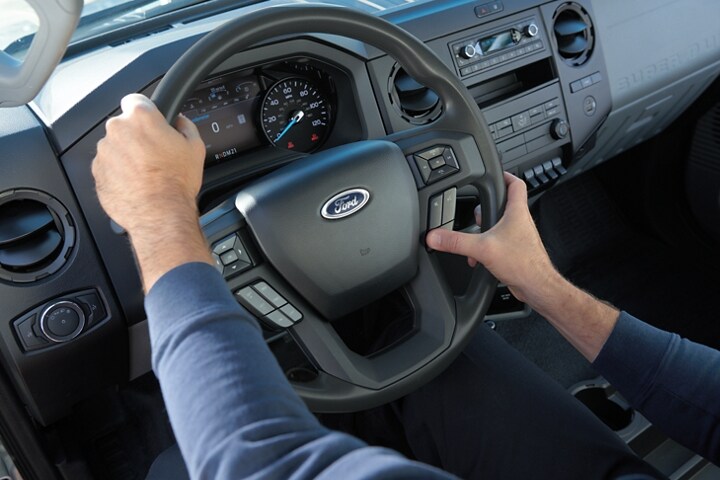 Mains utilisant les commandes sur le volant d’un camion poids moyen Ford 2025