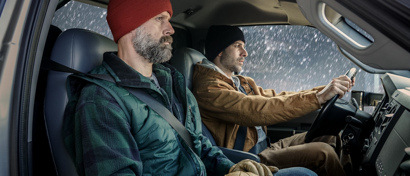Conducteur et passager portant des vêtements d’hiver à l’intérieur de l’habitacle du Ford F-750 2025 à cabine simple
