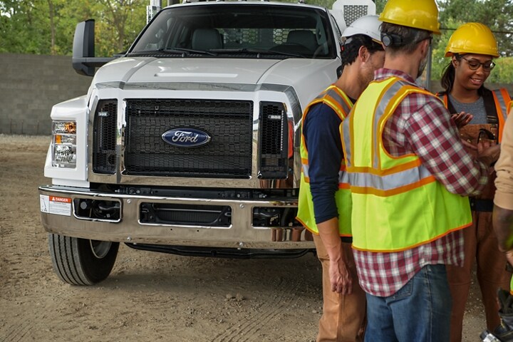 Travailleurs rassemblés devant un Ford F-750 2025 à cabine double aménagé en camion de mécanicien, en blanc Oxford