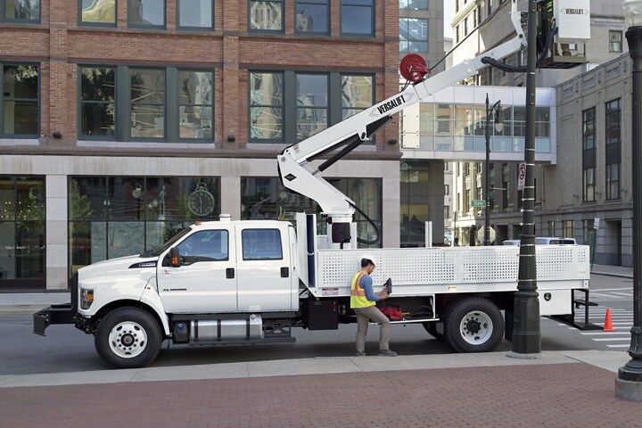 Travailleur réparant un lampadaire à l’intérieur d’une nacelle élévatrice aménagée sur le Ford F-750 2025 à cabine 6 places couleur blanc Oxford