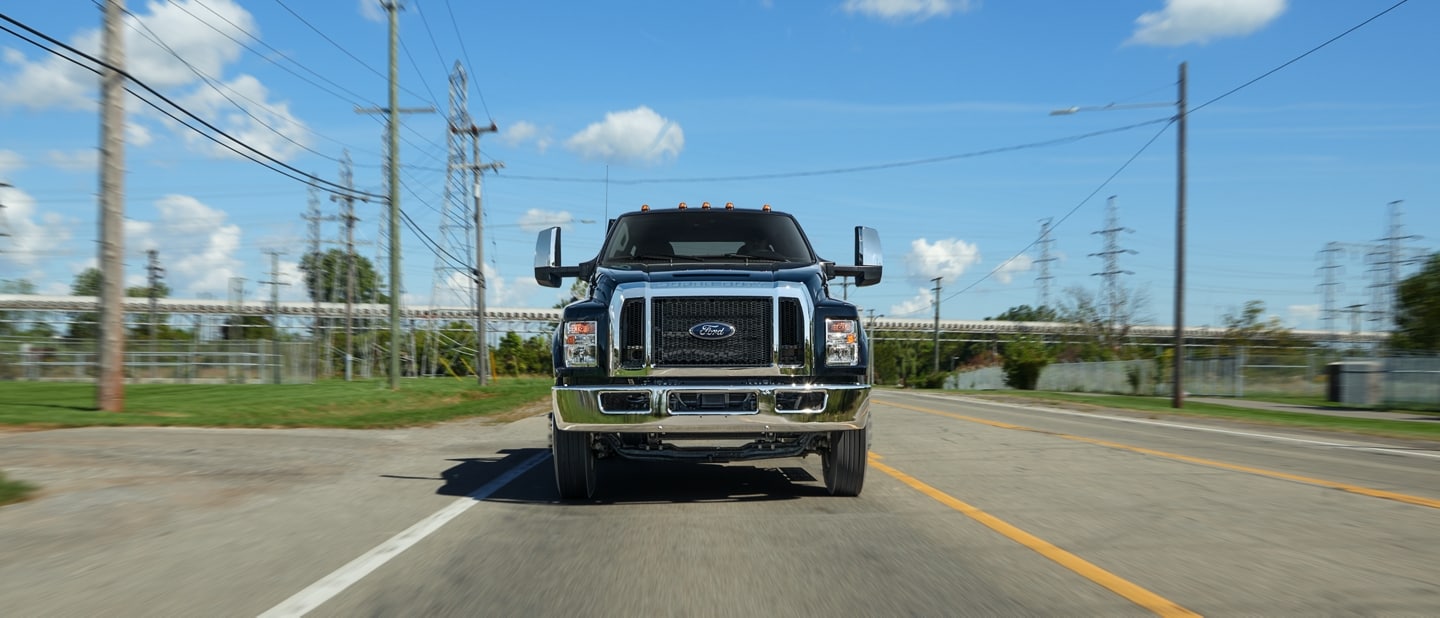 Ford F-750® 2026 à cabine 6 places en noir agate circulant sur la route près de lignes téléphoniques