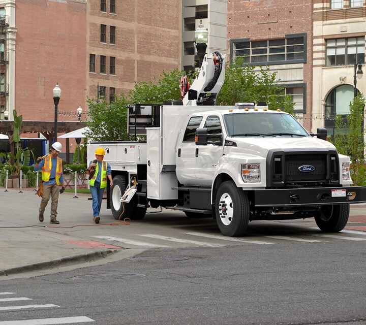 Travailleurs marchant près d’un Ford F-750® 2026 à cabine 6 places avec aménagement de nacelle élévatrice en blanc Oxford