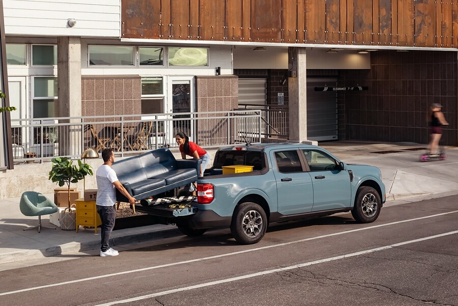Deux personnes chargeant un canapé et des articles ménagers dans la caisse d’un camion Ford Maverick® 2023
