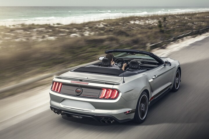 Une Ford Mustang® 2023 décapotable avec l’ensemble California Special sur une autoroute au bord de la plage