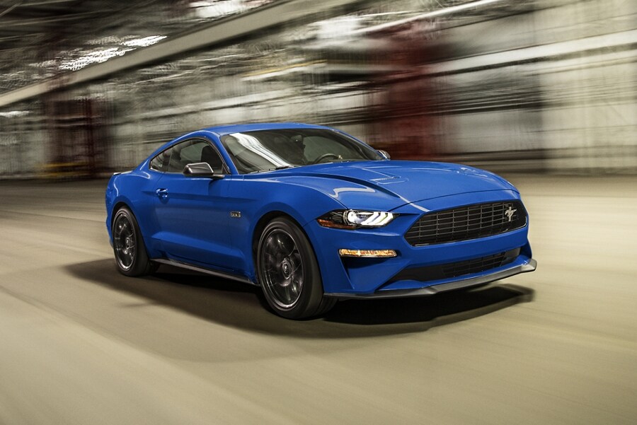Une Ford Mustang® coupé 2023 conduit à travers une structure de stationnement avec un arrière-plan flou