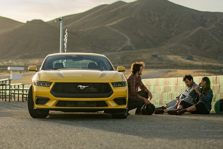 Ford Mustang® EcoBoost® Coupé 2024 en jaune soleil métallisé à trois couches (peinture à coût supplémentaire) stationné près de personnes