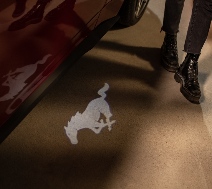 Des personnes s’approchant d’un modèle Ford Mustang® GT Premium 2024 avec détection d’approche accueillent l’éclairage extérieur