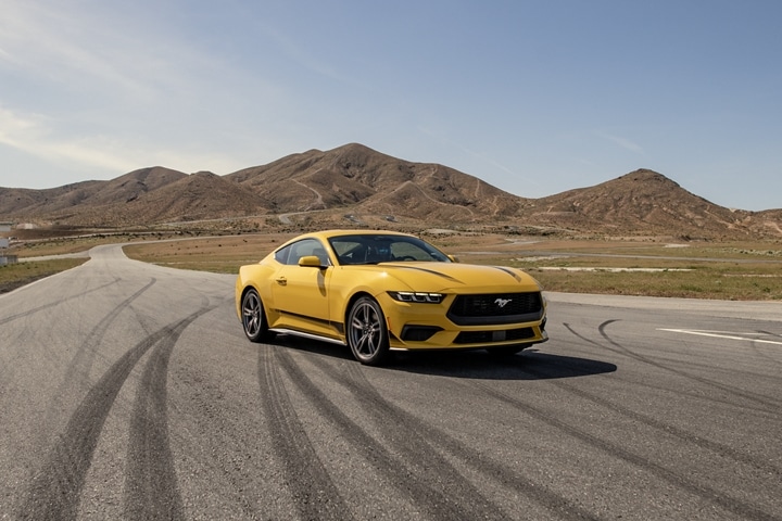 Ford Mustang® EcoBoost® Coupé 2024 en jaune soleil métallisé à trois couches (peinture à coût supplémentaire) stationné sur un parcours de course