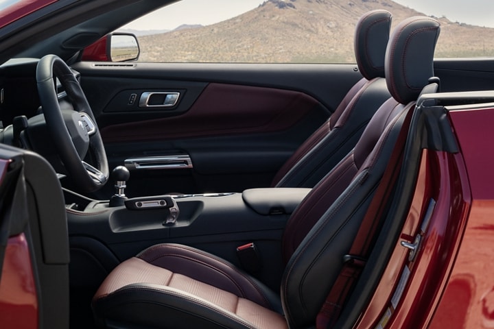 Ford Mustang® 2024 décapotable stationnée avec la portière du côté conducteur ouverte montrant l’intérieur rouge carmin en option