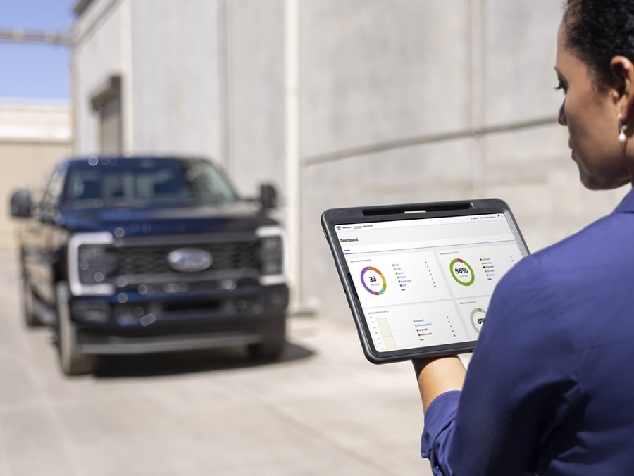 Femme regardant une tablette avec un modèle Ford Super Duty® F-250® XL 2025 avec ensemble décor en arrière-plan