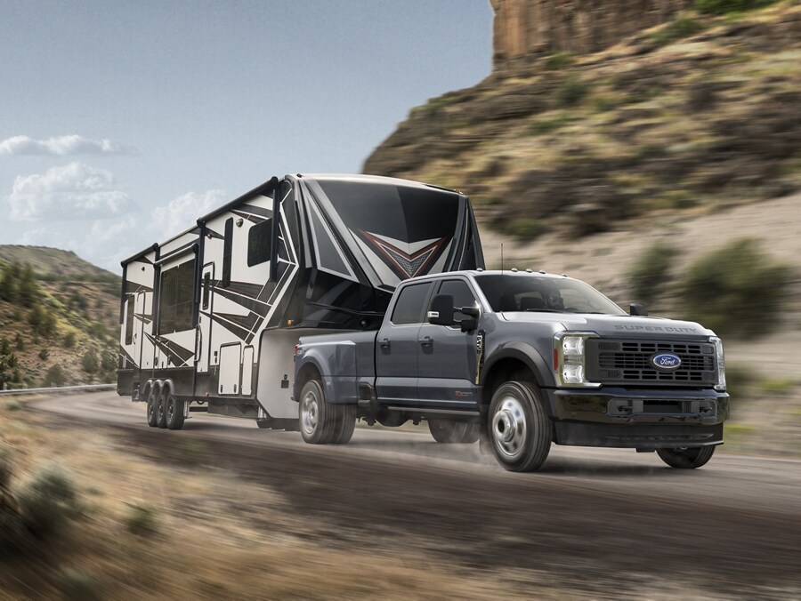 Modèle Ford F-450® Super Duty® Limited 2025 tirant une caravane sur un chemin de montagne