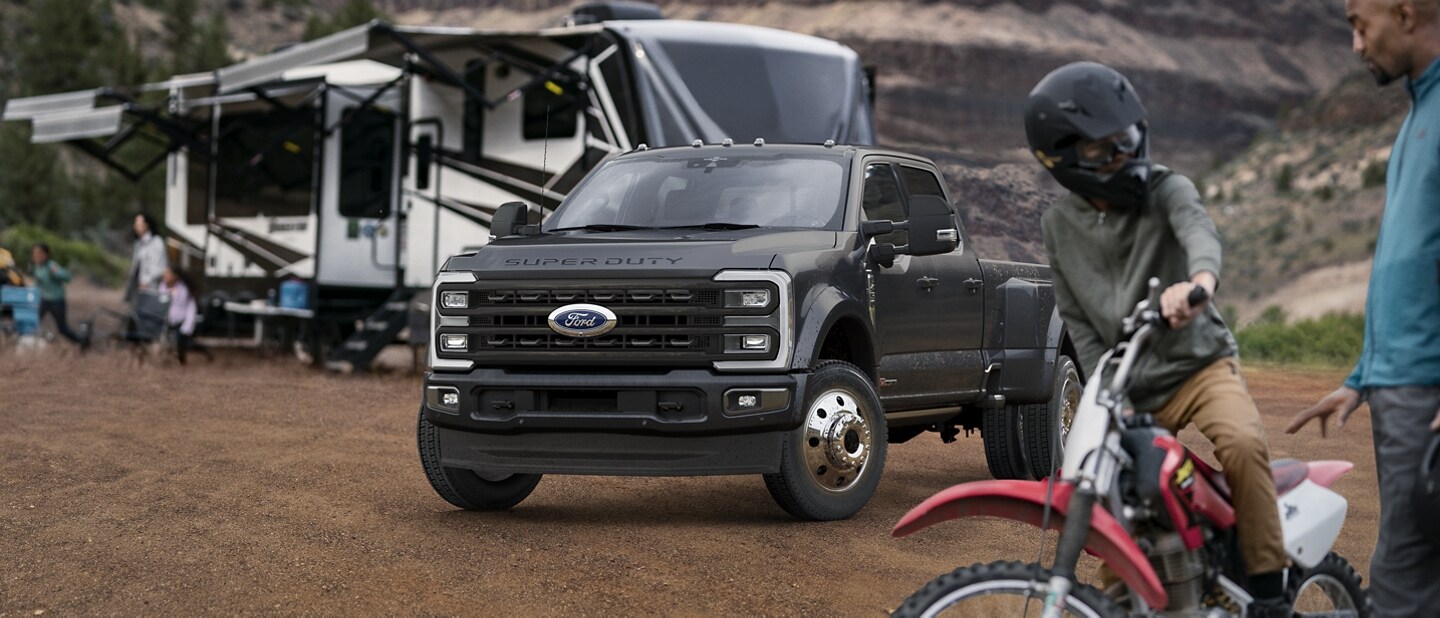 Un homme et un garçon debout près d’un Ford Super Duty® F-450® Limited 2025 stationné près d’une caravane