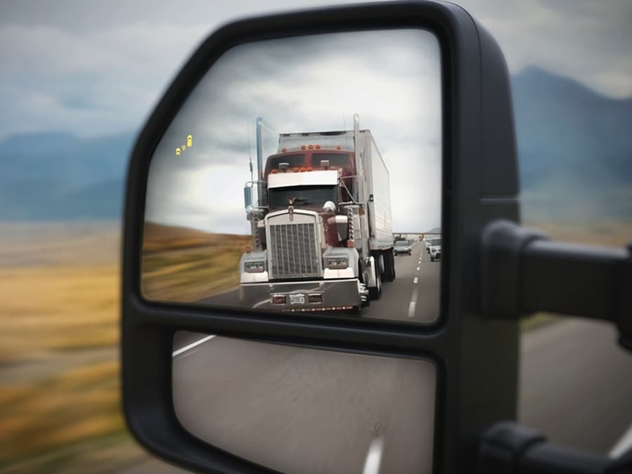 Gros plan du rétroviseur latéral montrant l’icône BLIS® allumée et une semi-remorque dans le reflet