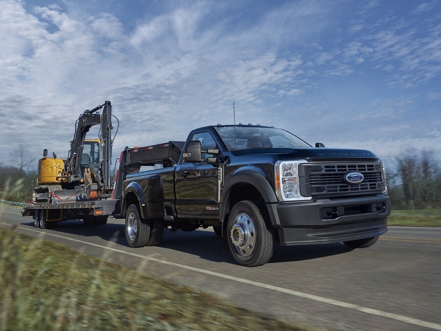 Modèle Ford Super Duty® F-450® XL à RAJ 2025 tirant un tracteur sur une remorque à plateau