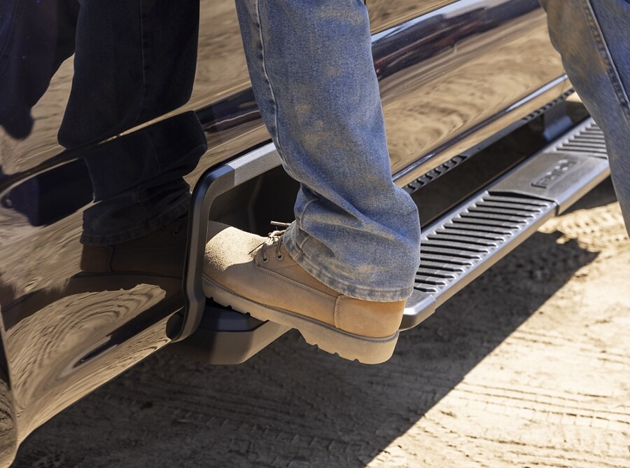 Gros plan d’une personne utilisant le marchepied latéral de plateau d’un camion Ford Super Duty® 2025