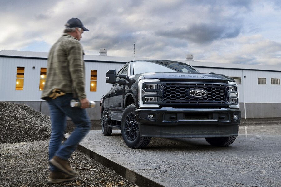 Homme marchant près d’un Ford Super Duty® LARIAT® 2025 avec l’ensemble décor noir