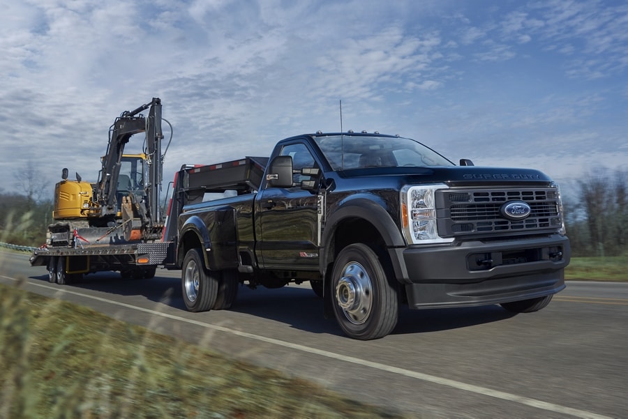 Camionnette Ford Super Duty® F-450® XL 2025 en noir agate tirant une rétrocaveuse sur une remorque