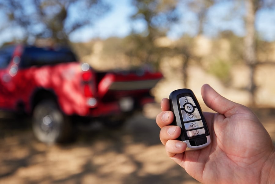 Main tenant un porte-clés avec un camion Ford Super Duty® King Ranch® rouge 2025 en arrière-plan