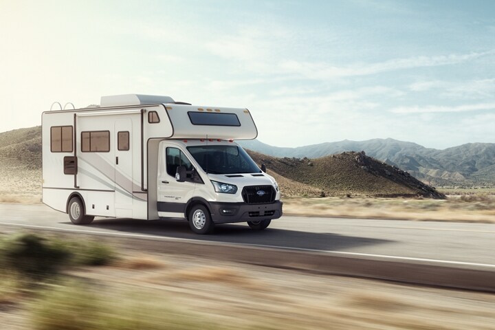 Côté d’une autocaravane de classe C sur un Ford Transit® tronqué 2023 circulant sur une autoroute désertique
