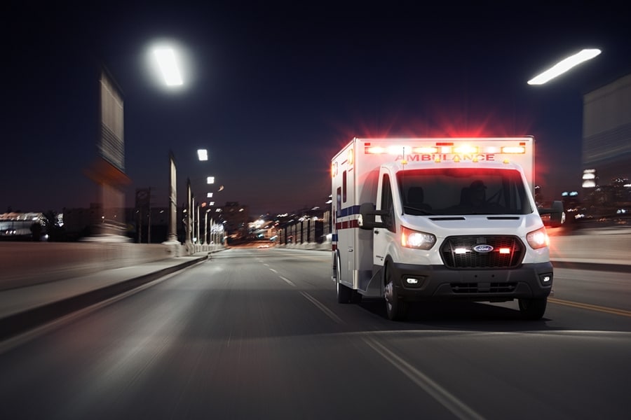 Modèle tronqué Ford Transit® 2024 avec carrosserie d’ambulance de type III circulant sur une route la nuit