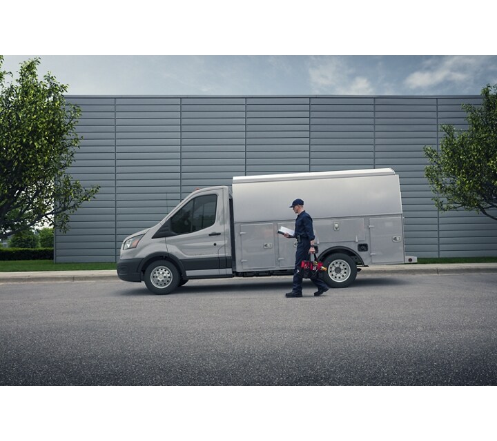 Personne portant des outils marchant près d’un modèle Ford Transit® à châssis-cabine 2024 avec aménagement de camion de mécanicien