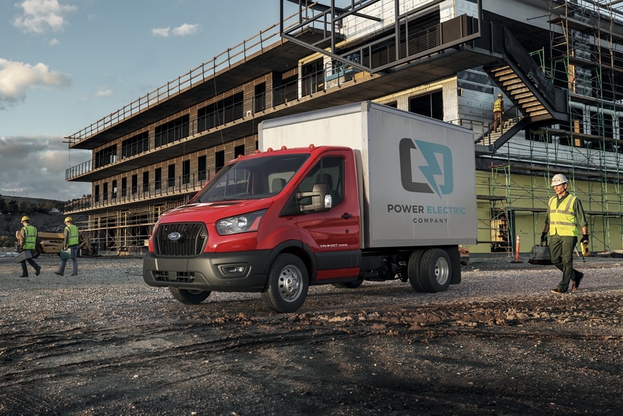 Modèle Ford Transit® châssis-cabine 2025 aménagé en camion fourgon stationné sur un chantier de construction avec une personne s’approchant munie d’un équipement de sécurité