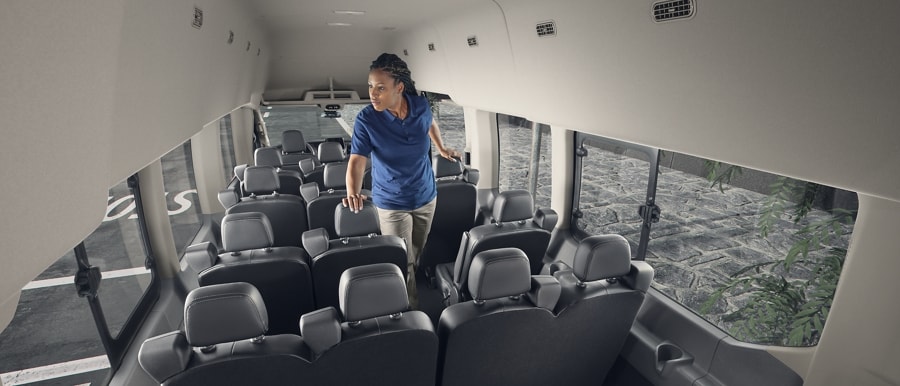 Une femme debout à l’intérieur d’une fourgonnette Ford Transit® 2023 avec 15 sièges