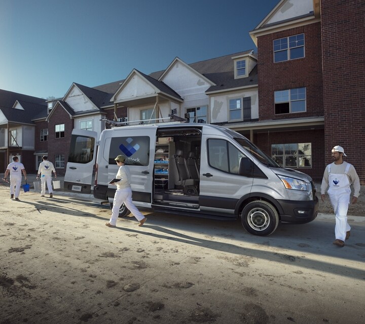 Une équipe de travail déchargeant une fourgonnette Ford Transit® 2023 près d’un chantier de construction