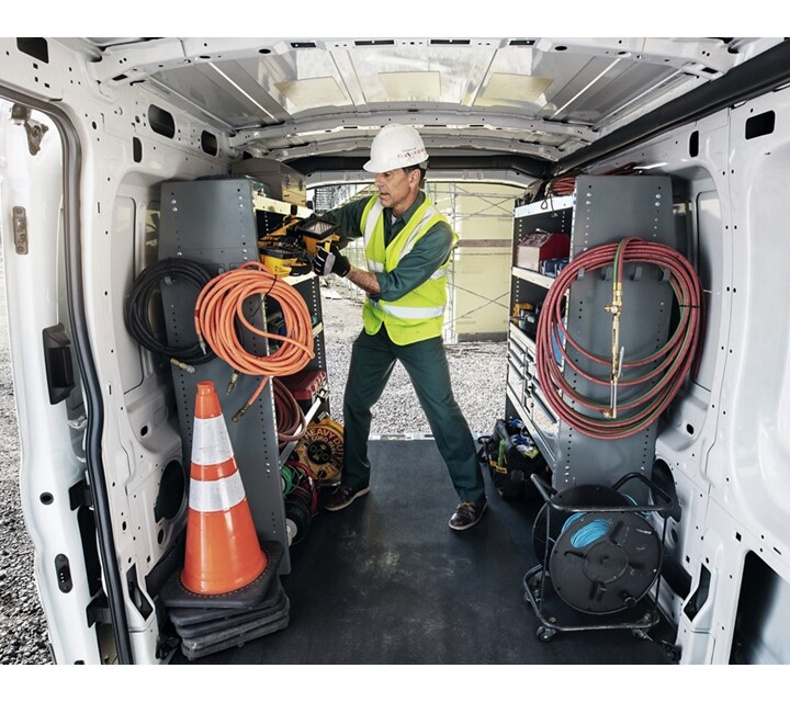 Une personne à l’arrière d’une fourgonnette Ford Transit® 2024 avec les portes de chargement ouvertes