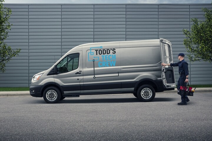 Un ouvrier ouvre l’arrière d’une fourgonnette Ford Transit® 2024 en transportant un sac à outils.