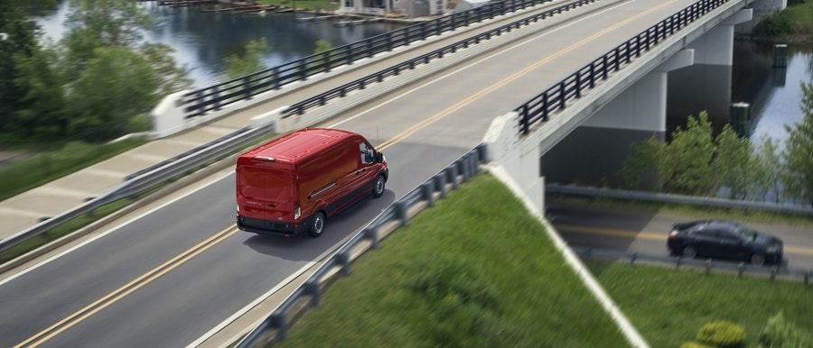 Une fourgonnette Ford Transit® 2025 en rouge course traversant un pont
