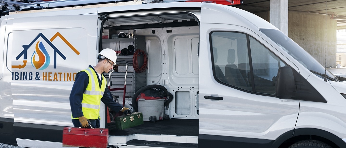 Homme déchargeant des outils d’une fourgonnette Ford Transit® 2025 avec portière coulissante électrique