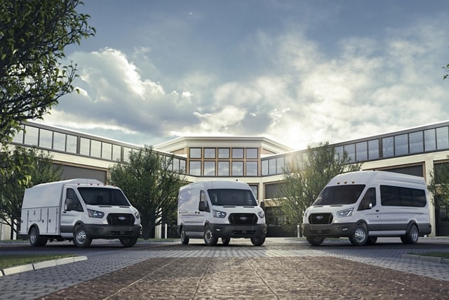 Trois fourgonnettes Ford Transit® 2025 stationnées à l’extérieur d’un immeuble de bureaux