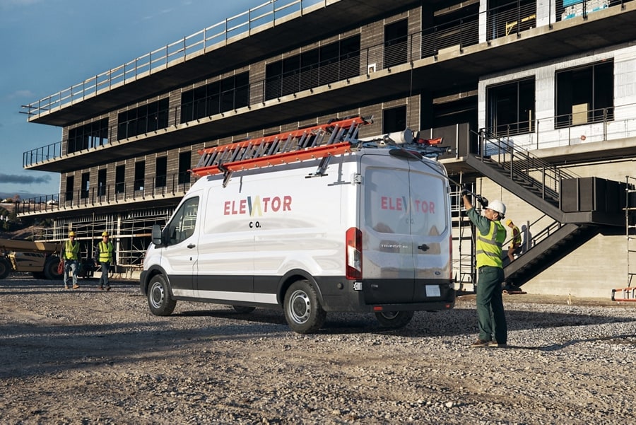 Une fourgonnette Ford Transit® 2025 stationnée sur un chantier avec des échelles dessus