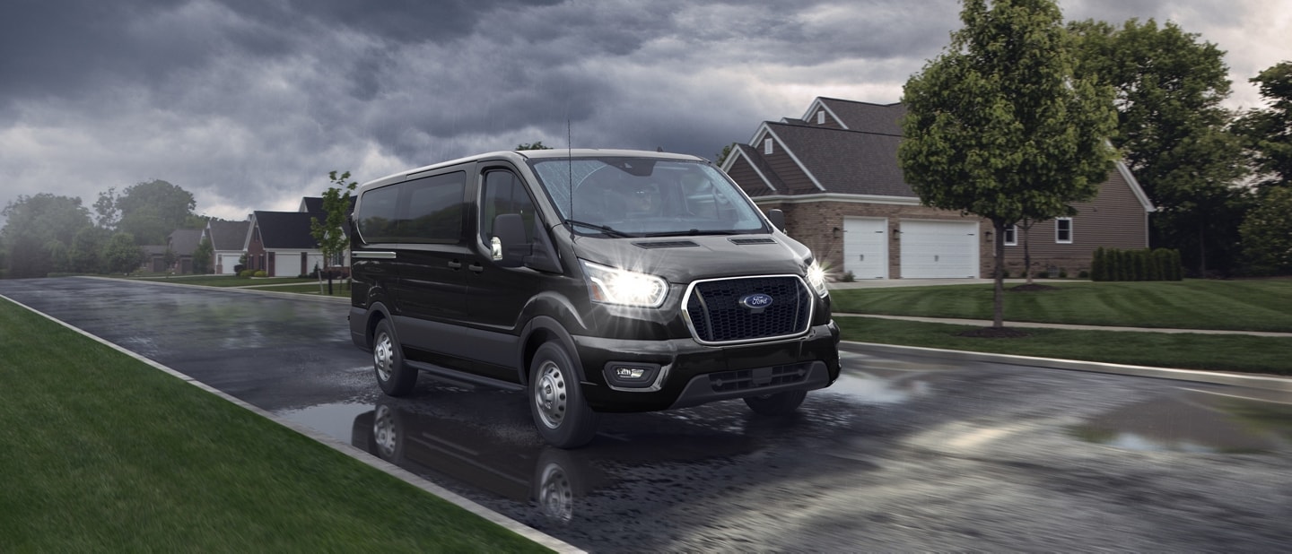 Une fourgonnette Ford Transit® 2025 circulant dans une rue par un temps pluvieux