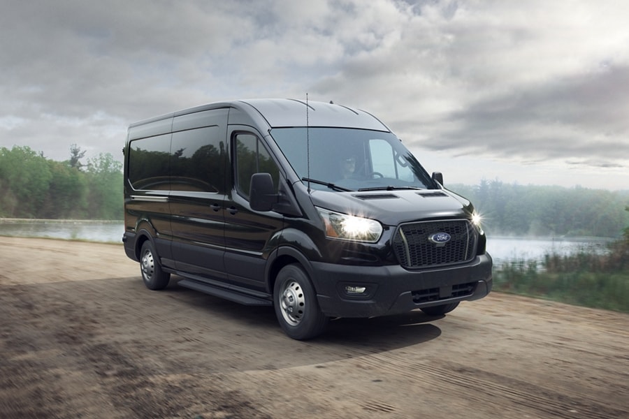 Une fourgonnette Ford Transit® 2025 en noir agate avec traction intégrale emprunte une route de terre